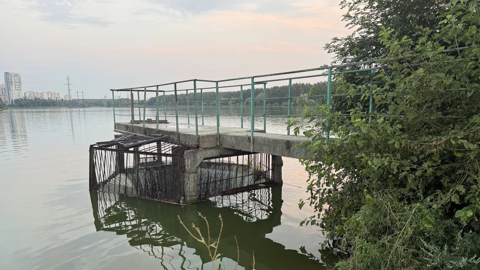Покинута бетонна водозабірна споруда з іржавими ґратами на водоймі, серпень 2026 року