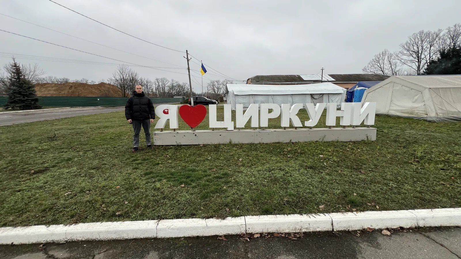 Знак «Я ♥ Циркуни» біля дороги на в'їзді в село, поруч — намети пункту незламності, грудень 2025 року
