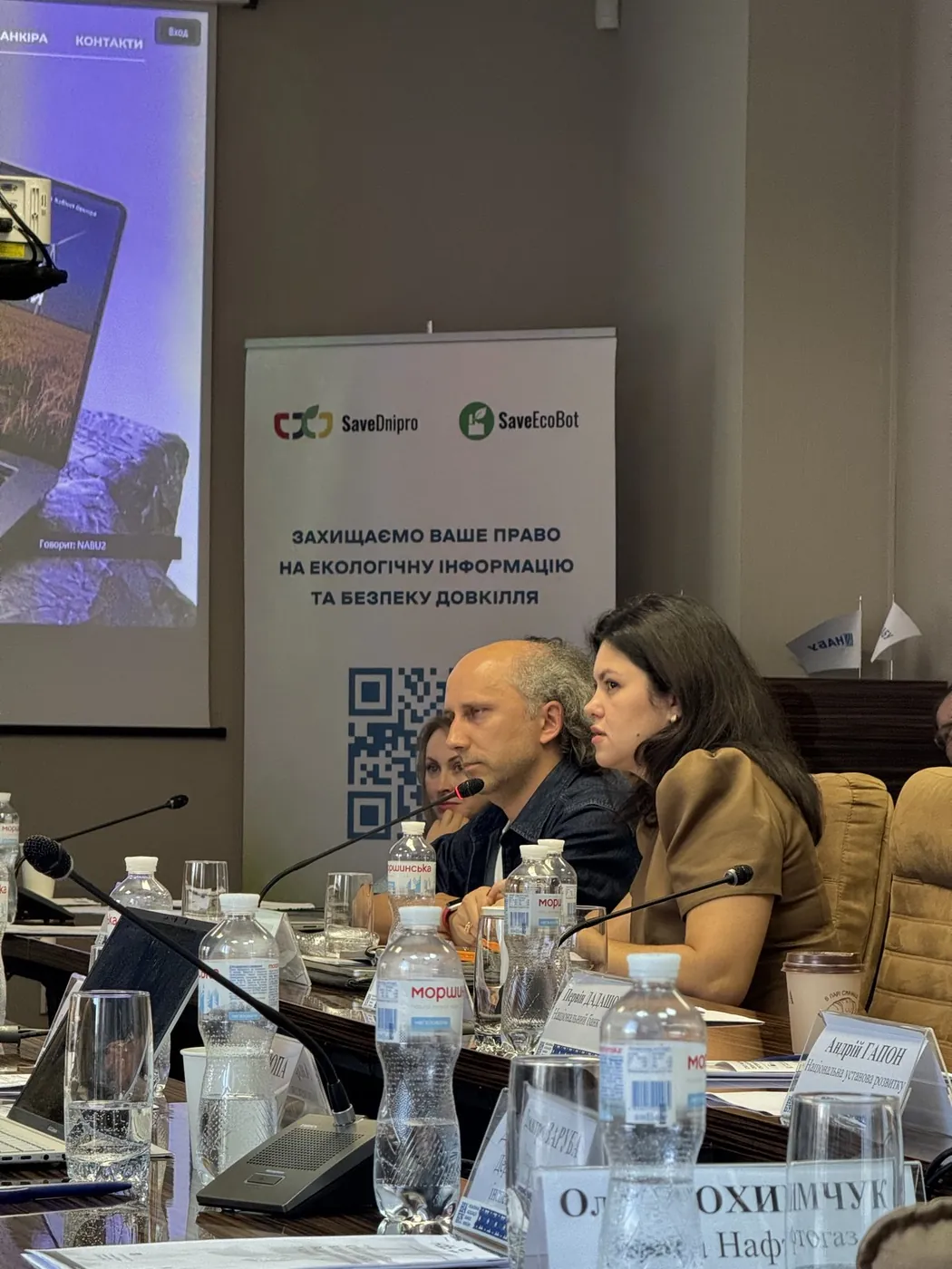 Учасники за столом, позаду банер організаторів SaveDnipro і SaveEcoBot