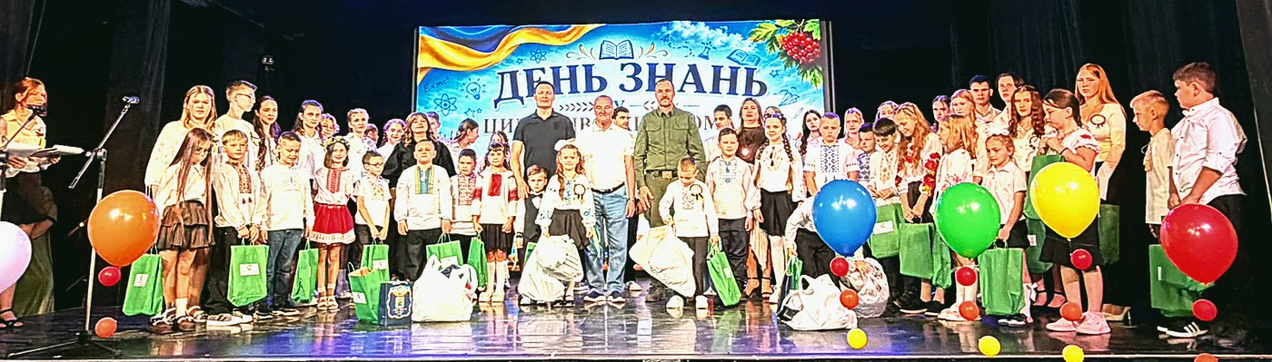 Діти з подарунковими наборами до нового навчального року на сцені