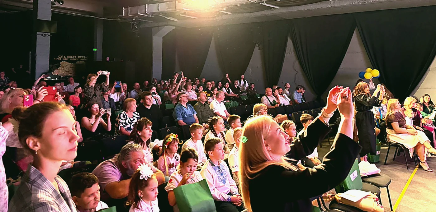 Зала під час святкового концерту, діти піднімають руки
