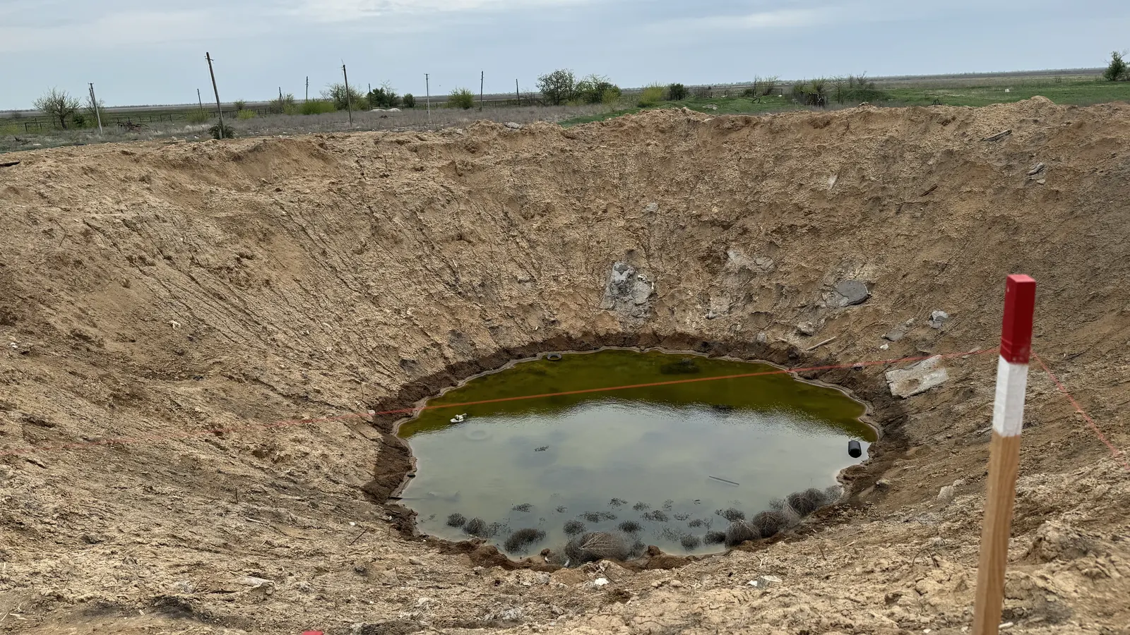 Вирва від влучання, заповнена водою, на полі Харківщини
