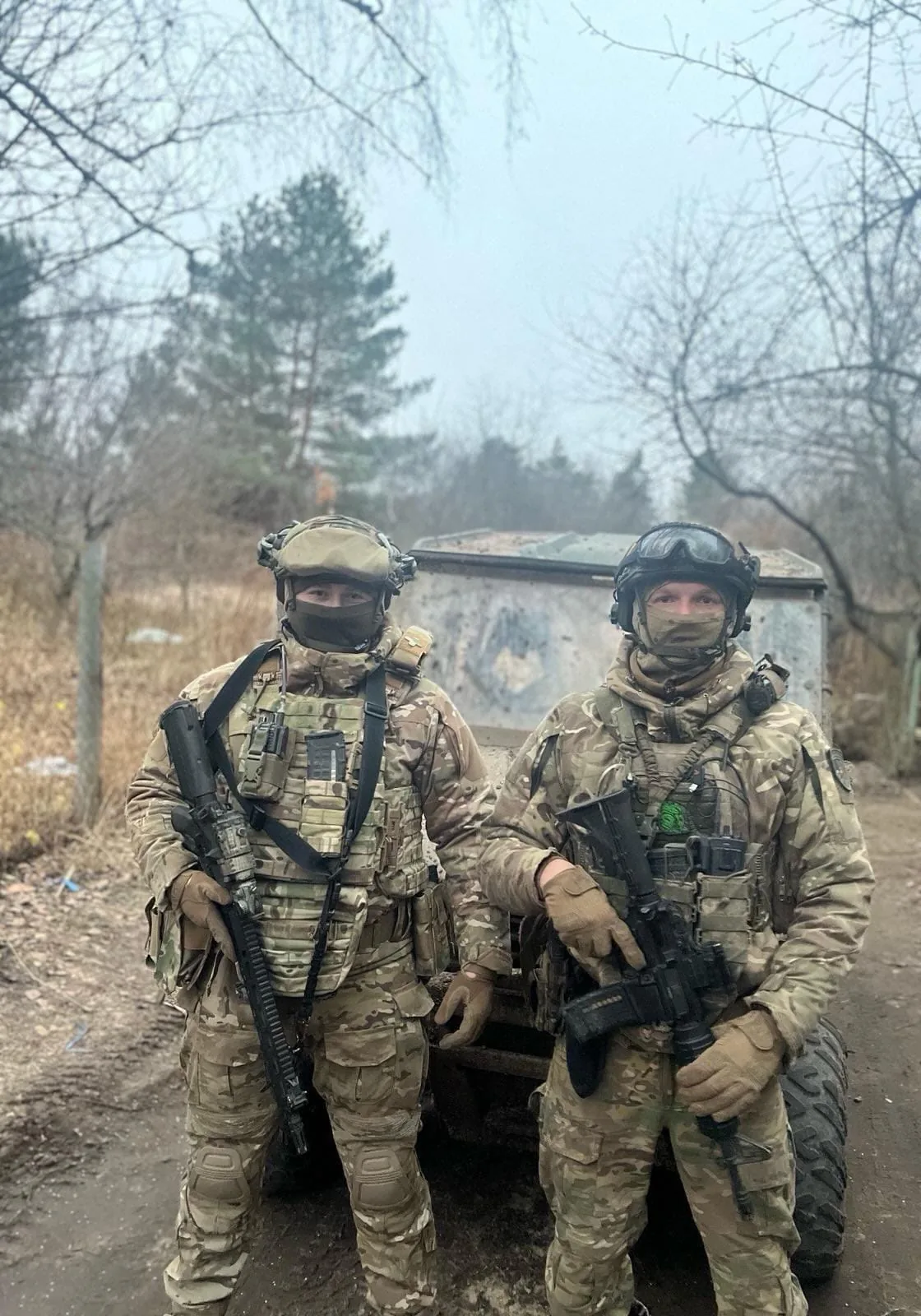 Двоє бійців бригади в шоломах і масках зі зброєю біля машини